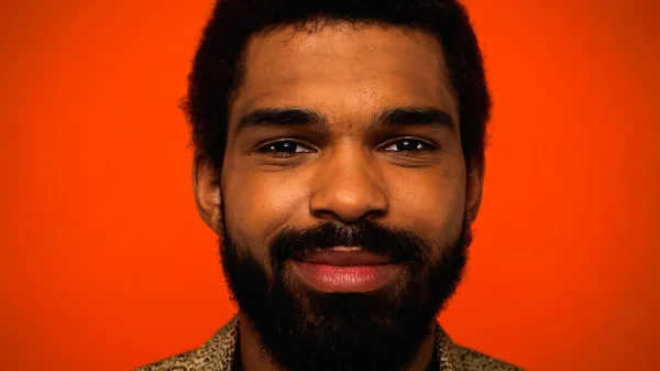 Nahaufnahme eines lächelnden und bärtigen afrikanisch-amerikanischen Mannes isoliert auf orange — Stockfoto