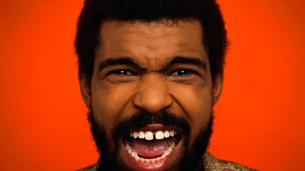 Primo piano di arrabbiato uomo afro-americano urlando isolato su arancione — Foto stock