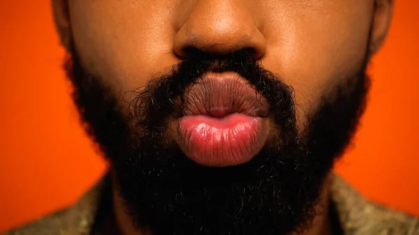 Vue recadrée de barbu afro-américain jeune homme boudant lèvres isolées sur orange — Photo de stock