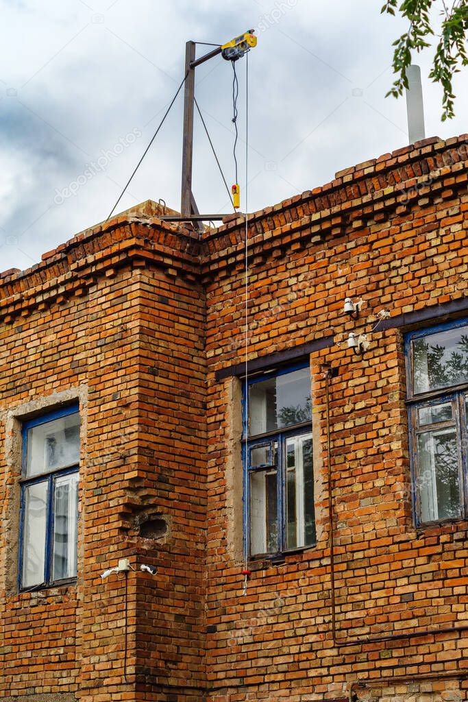 Hoisting winch with cable and control panel, on the roof of an old building. The picture was taken in Russia, in the city of Orenburg