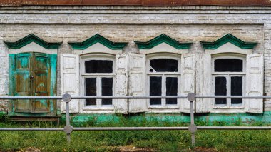 Eski bir tuğla binanın camlarında ahşap panjurlar ve platformlar var. Ön cephenin bir parçası. Fotoğraf Rusya 'da, Orenburg şehrinde çekildi.