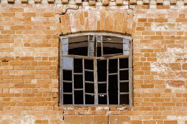 Terk edilmiş tuğla bir binanın duvarında kırık camlar olan ahşap pencere çerçevesi. Fotoğraf Orenburg bölgesindeki Pervokrasnoe köyünde çekildi.