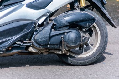 Konut caddesinde düşük hızda çalışan beyaz otomatik scooter.