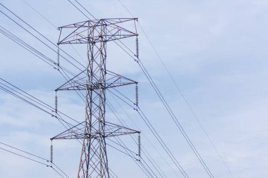 Elektrik kulesi için büyük ve uzun bir metal çerçeve yukarıdaki gerilmiş kablolar ile voltaj enerjisini dağıtır, açık ve parlak mavi gökyüzünün altında durur.