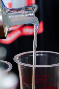 Bulanık ve yumuşak odaklı arka planı olan şeffaf plastik bir bardağa liçi şurubu döküyorum.