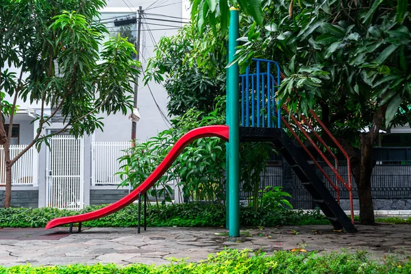 Şehir parkının oyun parkında kayan boş renkli metal çocuğun yan görüntüsü