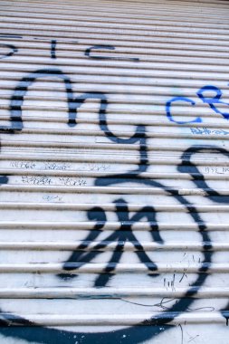 Vandalizm ve grafiti boyalı gümüş metal garaj kapısı.