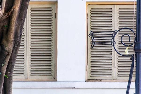 Sömürge mimarisinin beyaz duvar zemininde iki büyük kare beyaz eski ahşap kare pencere var.