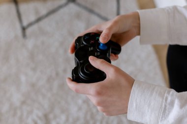 Kadın elleri oyun konsolundan bir joystick tutuyor.