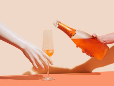 Paylaşım ve çeşitlilik kavramı. Yapay el, bir bardak buzlu içecek tutuyor ve kızlar ellerinde şampanya şişesini doldurmaya hazırlar. Bej ve terracotta arkaplanı