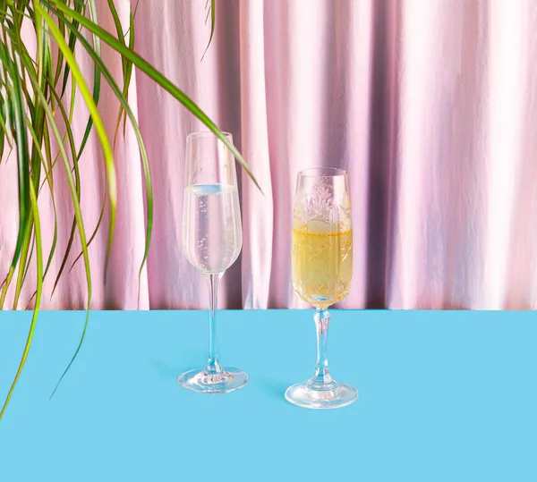 Eşsiz, lüks kristal bardaklardan yapılmış parti konsepti yanında tropikal yapraklarla düzenlenmiş köpüklü içecekler. Güzel zambak ipek ve mavi arka plan.