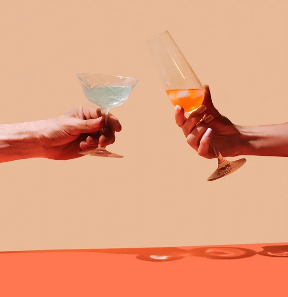 Party cheers concept. Two hands, man one holding antique glass and girl hand holding posh crystal glass with lovely drinks in it against beige and terracotta background