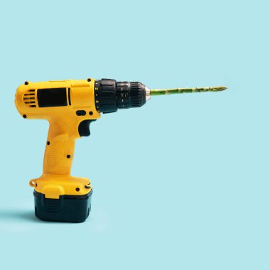 Vegan and vegetarian minimal concept. Yellow cordless drill with one fresh asparagus tip against a blue background.