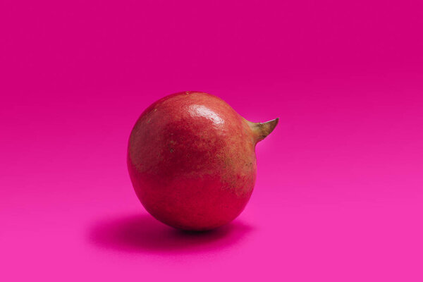 Minimal mediterranean fruit concept. An organic fresh pomegranate fruit placed against  a magenta background.