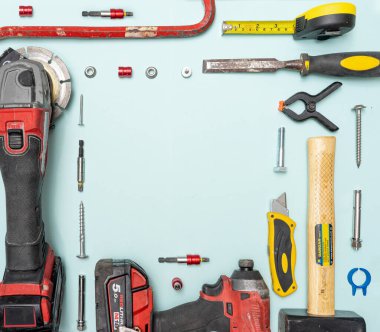 Dairesel testere, çekiç, metre, paslanmaz çoklu pense. Neşter, alet çantaları, tornavidalar ve pastel mavi arka planda diğer aletler. Üst Manzara. Kare yaratıcı kopyalama alanı.