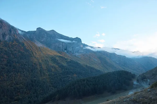 Dağ manzarası, yamaçtaki orman ve bulutlardaki kayalar, dağlık arazide akşam, yaz,