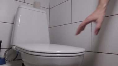 Banyodaki klozet kapağını açıp kapatıyor.