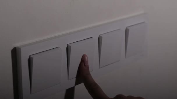 A kéz megnyomja a kapcsolót, a fény a szobában ki-be kapcsol, közelkép, oldalnézet — Stock videók
