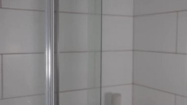 Duş kabininin cam kapısı açılıyor, banyo, şeffaf ekran, yakın plan.