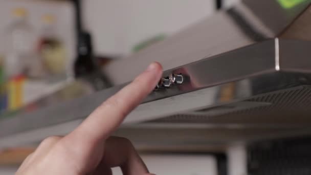 Hand drukt op de knop om het apparaat aan te zetten in de keuken, afzuigkap, close-up — Stockvideo