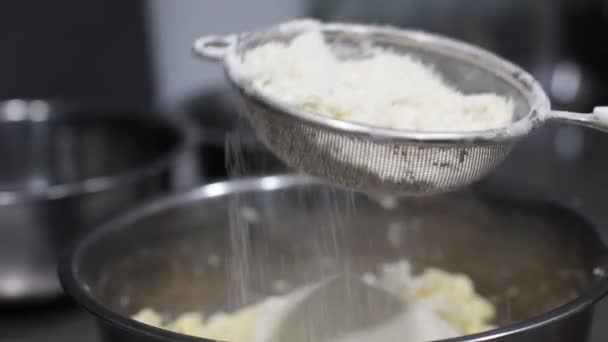 Les cuisiniers tamisent à la main la farine à travers un tamis dans un bol avec de la pâte, cuisson, vue latérale — Video