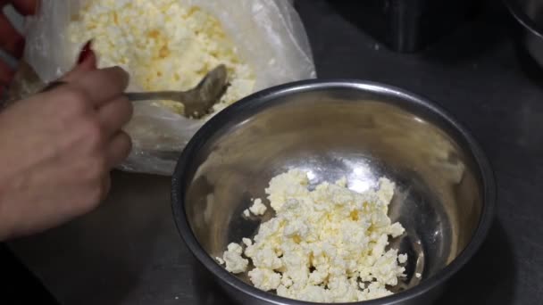 Une main met du fromage cottage avec une cuillère dans une casserole, d'un paquet dans un plat, vue sur le dessus — Video