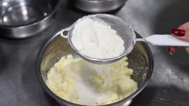 Les cuisiniers tamisent la farine à la main à travers un tamis dans un bol avec de la pâte, cuisson, vue sur le dessus — Video