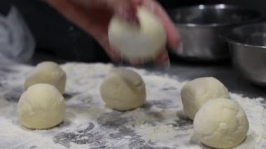 Aşçı hamur topları yapar ve un kaplı masaya koyar. Mutfakta tatlı yapar.