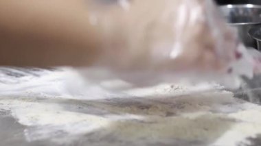 Aşçı masaya un dağıtır, hamur hazırlığı için masayı hazırlar.