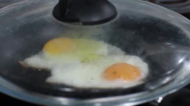 Kızartma tavasında kapağın altında kızarmış yumurta. Aşçı, mutfakta kapakla kızartma tavasını kapatır.