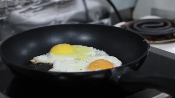 El cocinero rocía especias en los huevos revueltos en la estufa — Vídeos de Stock