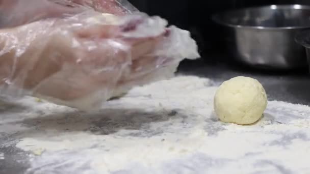O cozinheiro faz bolas de massa e as coloca prontas sobre a mesa coberta de farinha, fazendo sobremesa na cozinha — Vídeo de Stock