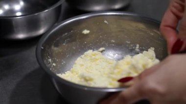 Aşçı süzme peyniri tabakta karıştırır, metal tabaklar, mutfakta yemek yapar.