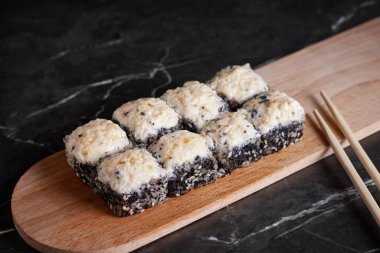 Bir porsiyon ekmek, Japon yemeği, masada suşi, Çin yemek çubukları, karanlık arka plan.