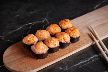 Bir porsiyon ekmek, Japon yemeği, masada suşi, Çin yemek çubukları, karanlık arka plan.