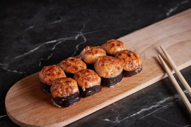 Bir porsiyon ekmek, Japon yemeği, masada suşi, Çin yemek çubukları, karanlık arka plan.