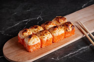 Bir porsiyon ekmek, Japon yemeği, masada suşi, Çin yemek çubukları, karanlık arka plan.