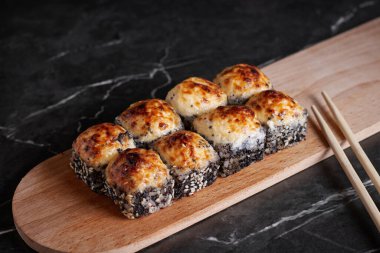 Bir porsiyon ekmek, Japon yemeği, masada suşi, Çin yemek çubukları, karanlık arka plan.