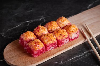 Bir porsiyon ekmek, Japon yemeği, masada suşi, Çin yemek çubukları, karanlık arka plan.