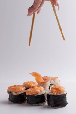 El ve Çin yemek çubukları, rulo diğer suşilerin üzerine düşer, porsiyon Asya yemeği, rulo