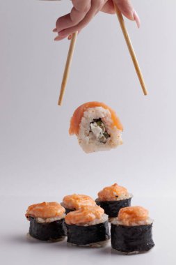 El ve Çin yemek çubukları, rulo diğer suşilerin üzerine düşer, porsiyon Asya yemeği, rulo