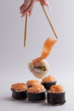 El ve Çin yemek çubukları, rulo diğer suşilerin üzerine düşer, porsiyon Asya yemeği, rulo