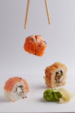 El ve Çin yemek çubukları, rulo diğer suşilerin üzerine düşer, porsiyon Asya yemeği, rulo