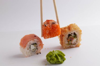 Bir el ve Çin yemek çubukları diğer suşilerin üzerinde bir rulo tutar, Asya yemeğinin bir kısmı, rulo yapar.