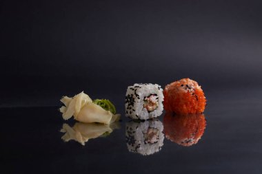 Masada birkaç farklı rulo var, Asya yemekleri, yan görüş, koyu arka plan, suşi, zencefil ve wasabi.