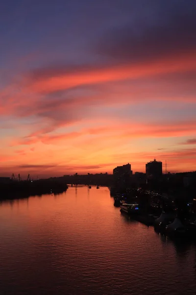 Puesta de sol en el río en la ciudad, rayos del sol, hora dorada, barcos y agua, paisaje nocturno — Foto de Stock