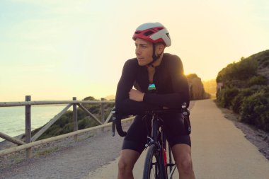 Gün batımında bir antrenman sırasında yolda mola veren bisikletçi..