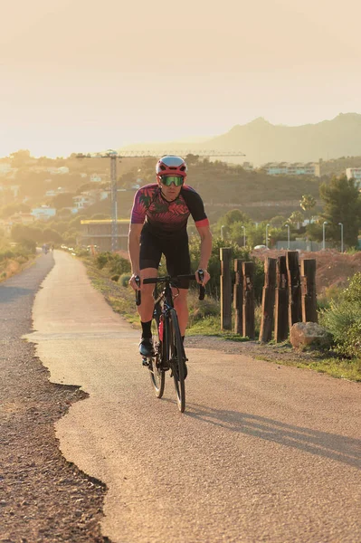 Bisikletçi alacakaranlıkta bir yola tırmanmaya çalışıyor.