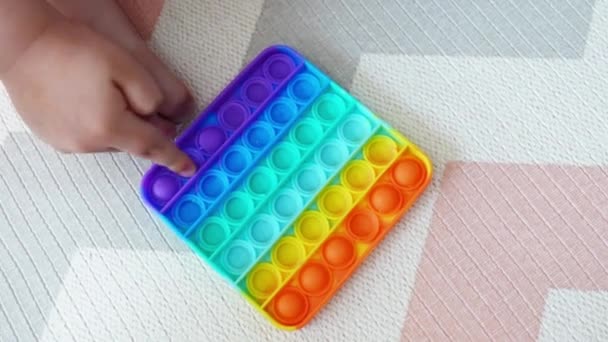 Antistress pop-it leksak. Närbild childs händer leker med regnbågens sensoriska spel. Färg silikon pop den leksak. Högst upp. Tryck pop bubbla fidget — Stockvideo