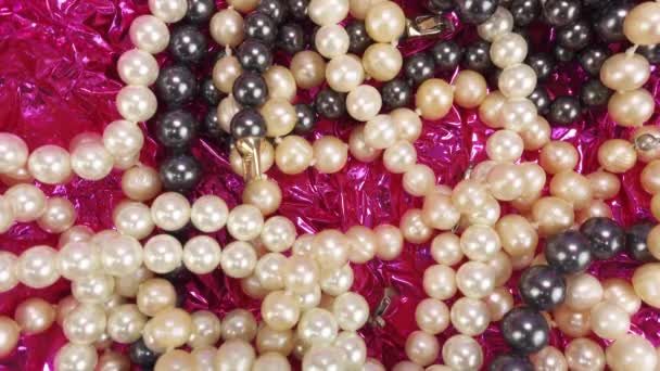 Forgó felvételek gyönyörű természetes fehér és fekete gyöngyökről. Sok gyönyörű női gyöngy karkötők, nyakláncok és láncok.Ékszerek lila fukszia háttér — Stock videók
